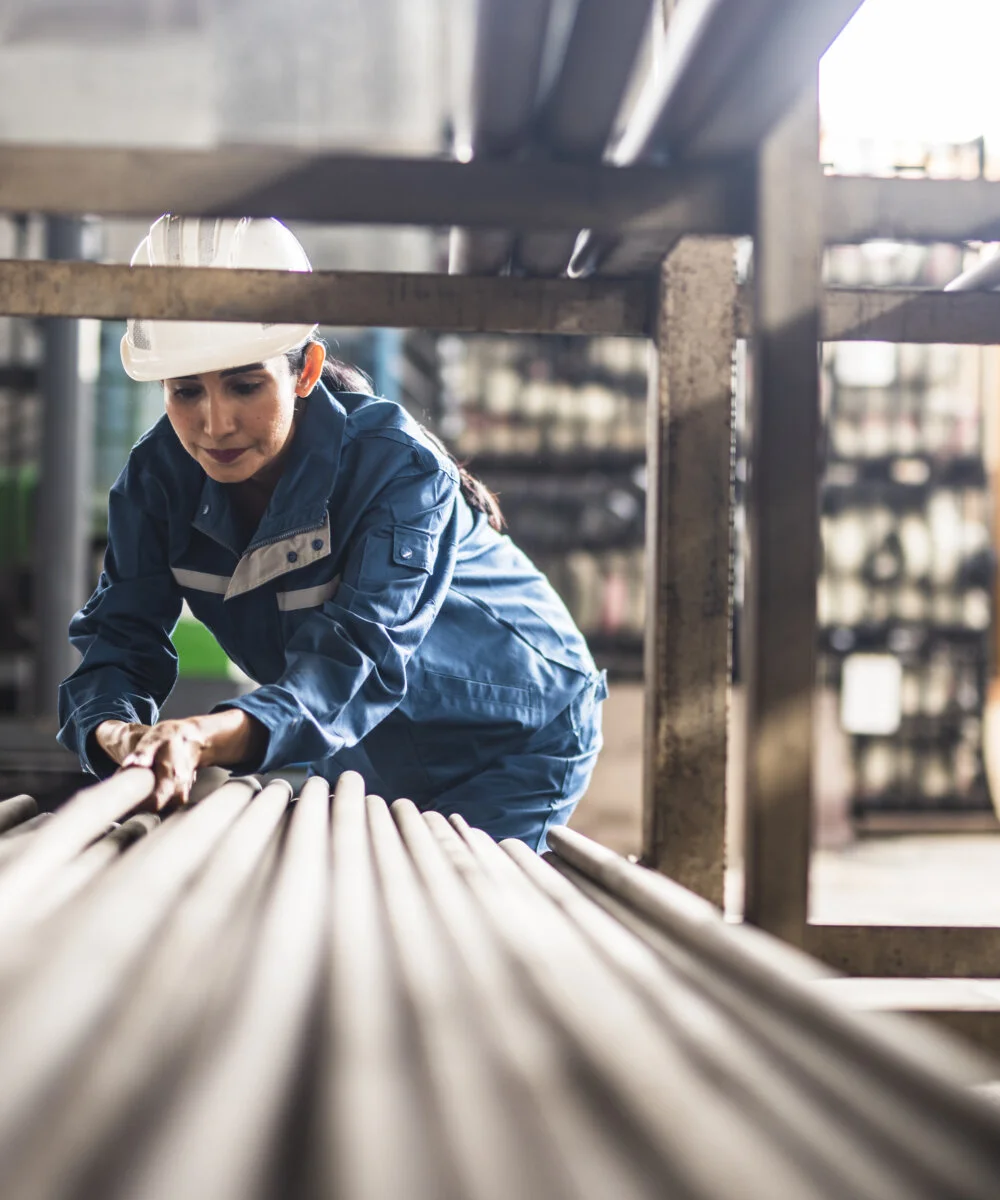 Female Steel Factory Worker at work moving steel poles